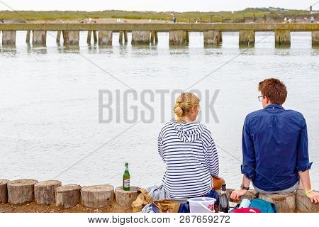 Suffolk, Uk - September 8, 18 - A Couple Sitting At The Southwold Harbour, Facing The Junction Of Of