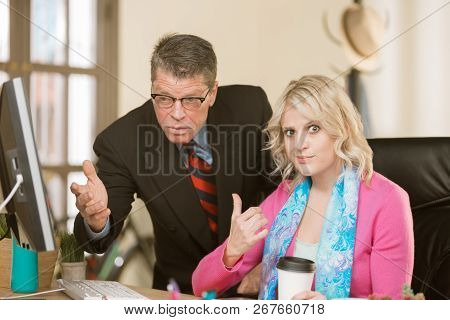 Woman Seated At Desk Gesture Towards Incompetent Male Colleague