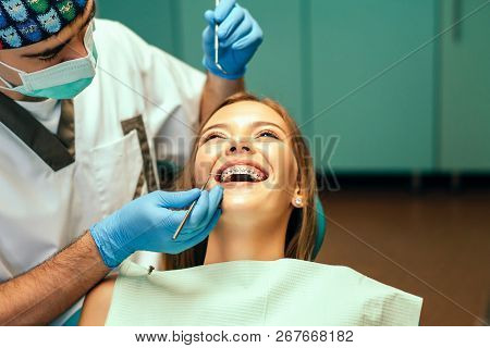 Dentist Examine Female Patient With Braces In Denal Office.