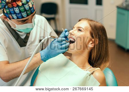 Dentist Examine Female Patient With Braces In Denal Office.
