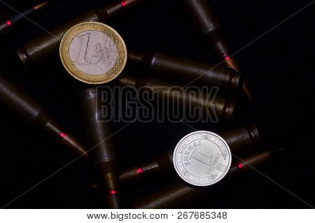 One Euro And Ukrainian Hryvna Coins With Rifle Military Ammo On Black Background. Symbolizes War For