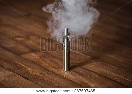 Electronic Cigarette On A Wooden Table. Smoke.