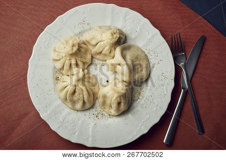 Traditional Chinese Or Asian Food, Steamed Dumpling Served On White Plate With Fork And Knife