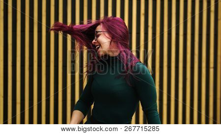 Cute Young Girl Dancing On Background Of Simple Geometric Pattern. Girl Has Eggplant Hair Flying In 