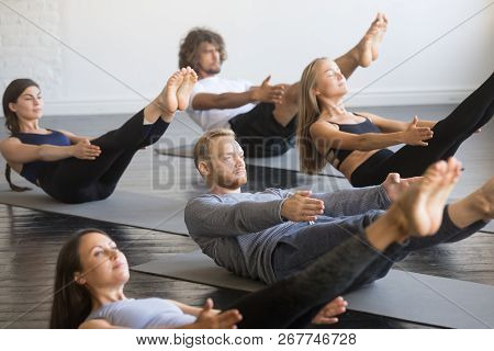 Group Of Young Sporty People In Paripurna Navasana Pose