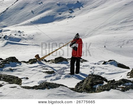 Homem tocando trompa de alp nas montanhas nevadas