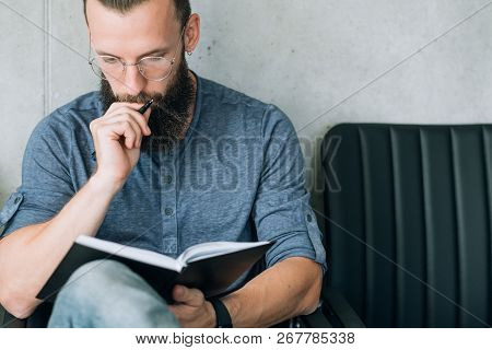 Focused Concentrated Man Reading Notes In Notepad. Data Analysis Or Business Strategy Development.