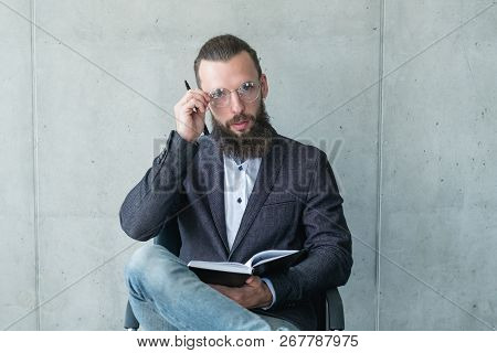 Smart Serious Professor Or Examinator. Bearded Man In Suit Jacket Rearranging His Glasses