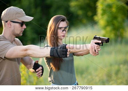 The Instructor Teaches The Girl To Shoot A Pistol At The Range
