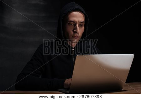 Portrait Of Hacker In Black Hoodie Using Laptop, Cuber Security Concept