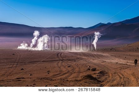 View of wide sunshine mountanious Bolivian desert and couple looking at the steaming geysers