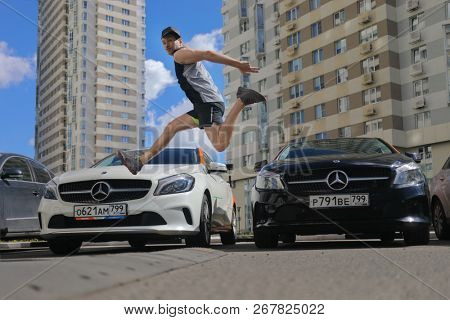 MOSCOW - JUN 20, 2018: Sporty guy (with MR) jumps near two Mercedes Benz cars of Moscow carsharing company You drive, carsharing is system of short-term car rental