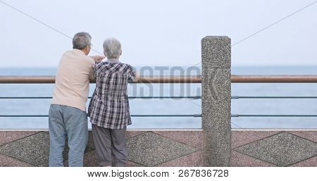 Old couple chatting and looking at the sea together