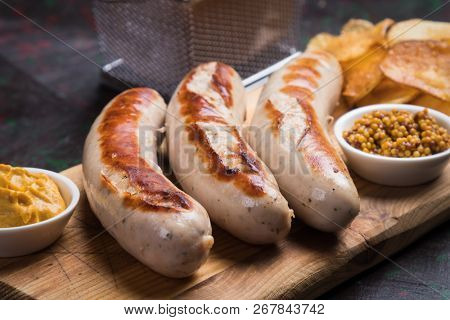 Grilled german sausages with mustard and fried potato chips