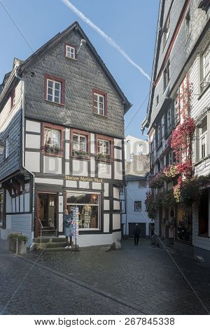 Monschau, Germany, October 2018 - Picturesque Timber Framed Buildings With A Lady Looking At A Greet