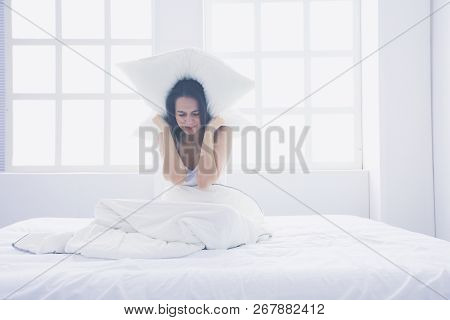 Young Caucasian Woman Covering Her Head And Ears With Pillows.