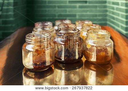 Glass Jars With Variety Of Remains Of Jam On Gloden Surface
