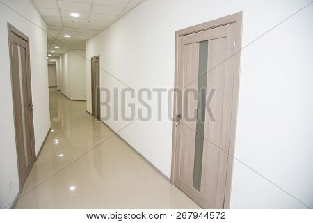 Empty Office Corridor With Many Doors Of Light Wood