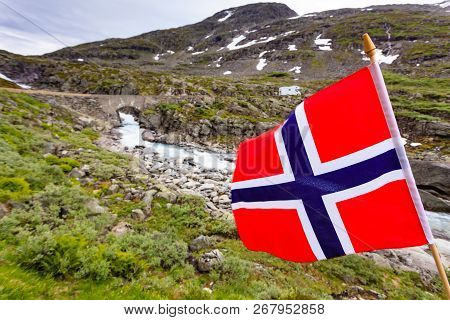 Norwegian Flag Waving On Wind And Camper Car In Mountains In The Background. Travel, Holidays And Ad