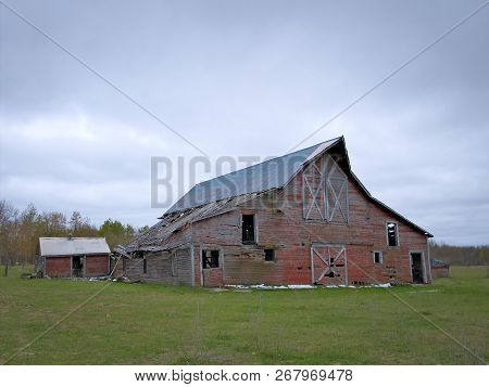 Dreary Abandoned Dilapidated Farm Barn With Cloudy Skies In Northern Minnesota
