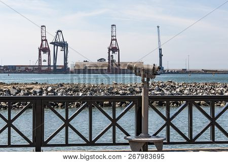 Sightseeing Binoculars Overlook The Harbor In Ensenada, Mexico, With Panamax Shipping Cranes At The 