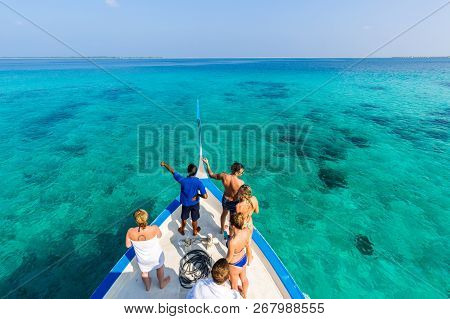 Tour Guides And Tourists On A Maldivian Dhoni Boot Looking Over Blue Sea Water. Snorkel Or Diving Tr