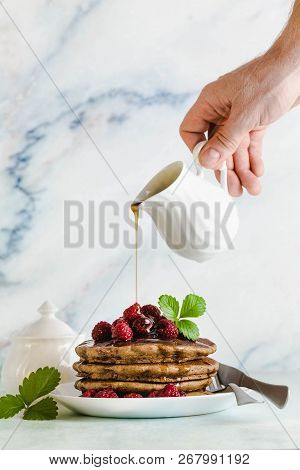 Pouring Maple Syrup Over Gluten Free Green Buckwheat Pancakes With Fresh Berries. Delicious Vegan Br