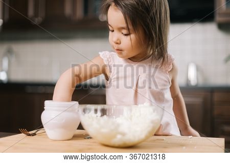 Funny Beautiful Little Girl Is Taking Salt From The Salt Cellar With Fingers To Add To The Dough In 