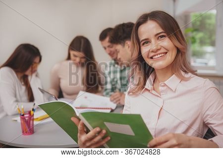 Close Up Of A Lovely Happy Young Female Student Smiling To The Camera Over Her Shoulder, Enjoying St