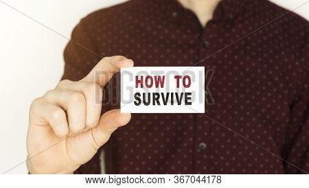 Businessman Holding A Card With Text How To Survive.