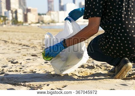 Clean City Beach From Trash. Woman Hand Picking Up Empty Soft Drinks Cans Trash And Plastic Bottles 