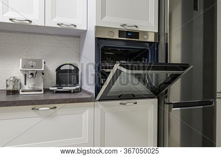 Electric appliances such as espresso coffee maker, sandwich maker and oven in modern minimalistic white kitchen interior