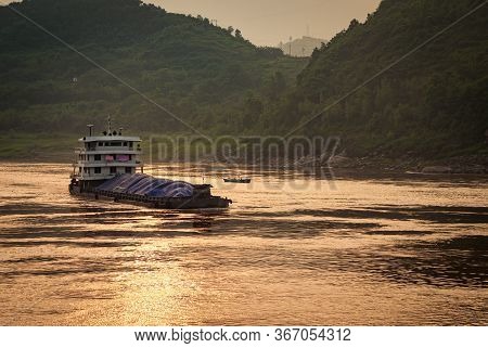 Chongqing, China - May 8, 2010: Evening Light On Yangtze River. Loaded Barge Sails On While Golden S