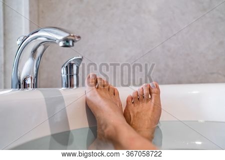 Woman taking a hot bath at luxury hotel - spa wellness body care relaxation. Closeup of happy feet.