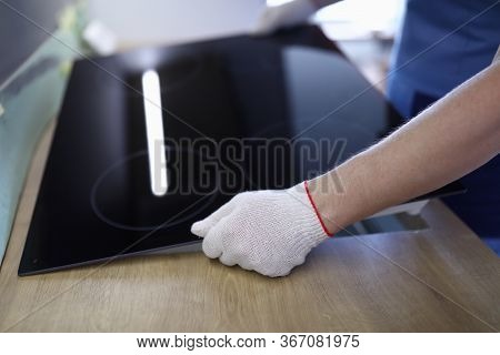 Close-up Of Professional Worker Setting Cookstove In Kitchen Room. New Modern Cooker. Man Wearing Pr