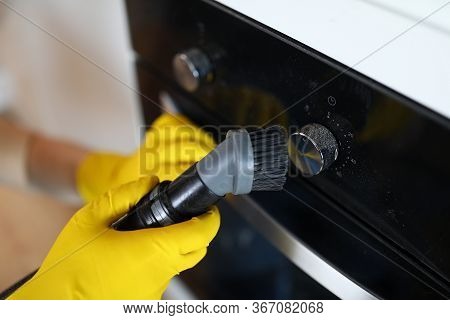 Close-up Of Male Hands In Yellow Gloves Vacuuming Cookstove Handle With Special Vacuum Cleaner After