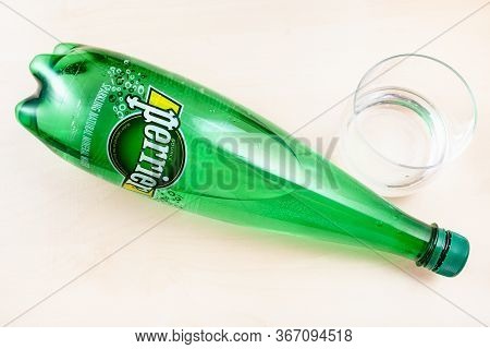 Moscow, Russia - May 10, 2020: Top View Of Lying Plastic Bottle Of Perrier And Glass With Water On B