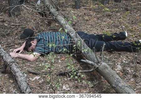 A Body In The Woods. A Dead Man In A Blue T-shirt And Trousers Is Pinned Down By A Fallen Tree. Conc