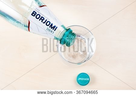 Moscow, Russia - May 10, 2020: Top View Of Pouring Borjomi Water From Plastic Bottle In Glass On Lig