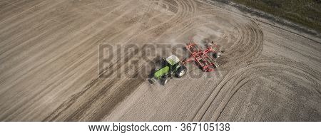 Aerial View Of A Clean Field In Which The Tractor Makes Vertical Tillage. Red Tillage Equipment And 