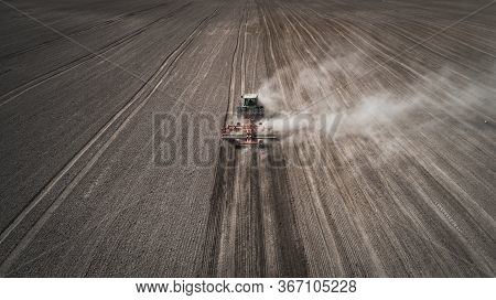 Aerial View Of A Clean Field In Which The Tractor Makes Vertical Tillage. Red Tillage Equipment And 