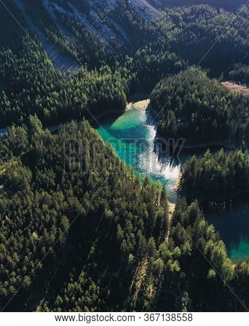 A Drone Shot Of An Alpine Valley In Austria. The Valley Has A Green Lake In The Middle. A Headland I