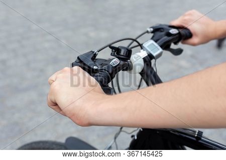 Young Active Man On A Bike Resting His Hands On The Handle Bars, Concrete Background. Speedometer An