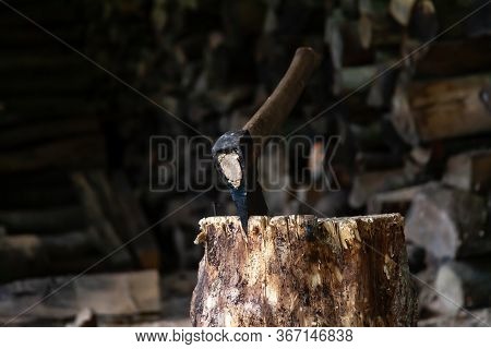 Old Axe Resting In A Wooden Firewood Log Closeup. Steel Axe Stuck In The Chopping Log. Cutting Timbe