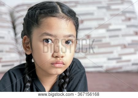 Close-up A Little Asian Girl In A Black Braid On The Sofa