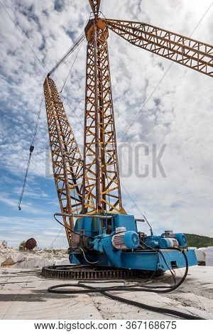 Old Soviet Crane On The Slewing Gear In An Abandoned Marble Quarry. High Boom Crane. Thick Cable Goe