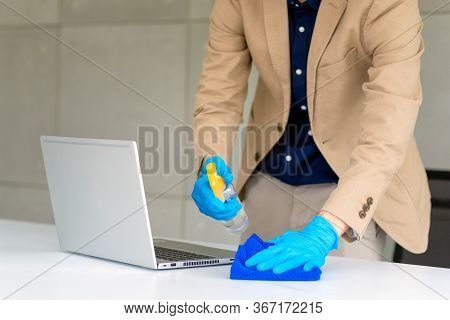 Business Woman Wearing Mask And Using Personal Sanitizer To Cleaning His Table In Office To Keep Hyg
