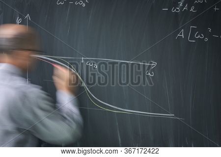 Math teacher drawing   fuction graph on a blackboard during mathclass (motion blurred image)