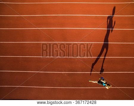 Shot of a young male athlete training on a race track. Sprinter running on athletics tracks seen from above