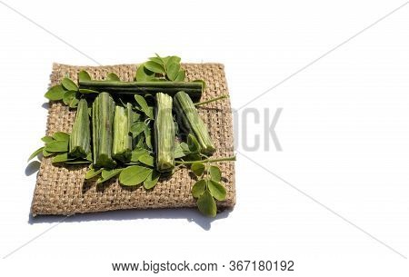 Drumstick Pods And Moringa Oleifera Leaves On Burlap Fabric Isolated On White Background In Horizont